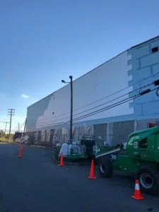 Commercial EIFS installation in progress with boom lift on large building wall in East Brunswick, NJ by CMB Stucco