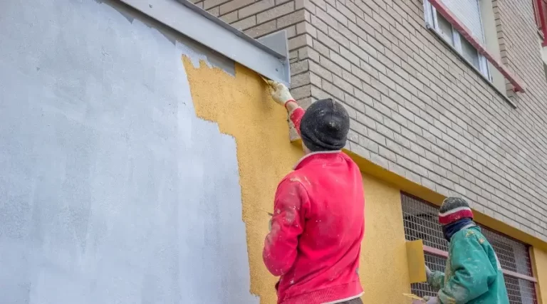 person applying plaster on house exterior